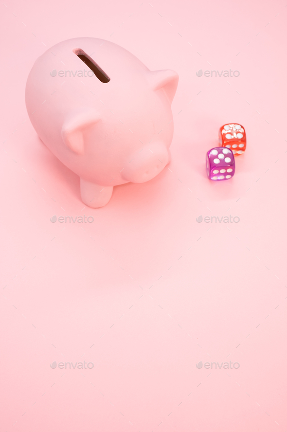 A piggy bank and dice on a pink background with space for your