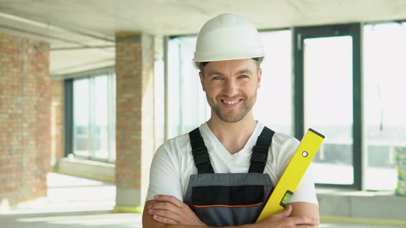 Portrait of an Engineer in a Helmet with Yellow Balance Ruler at a Construction Site alt