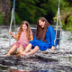a woman and a young girl are swinging across a fast-flowing river, laughing and splashing with water - PhotoDune Item for Sale