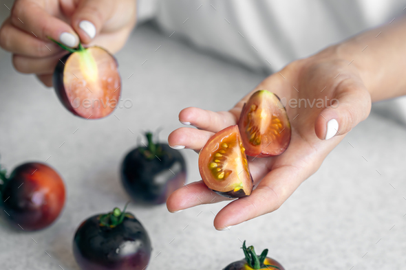 Black tomatoes in female hands close-up, cooking in the kitchen. Stock ...