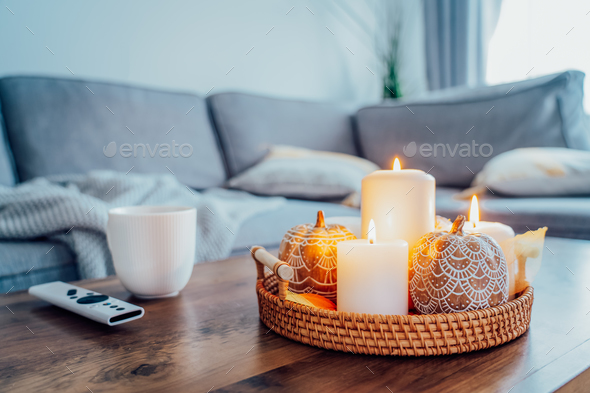 Autumn fall cozy mood composition for hygge home decor. Orange pumpkins, burning candles,