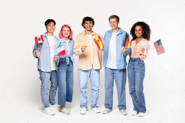 Happy exchange students in language school. Smiling multiracial friends holding different flags over