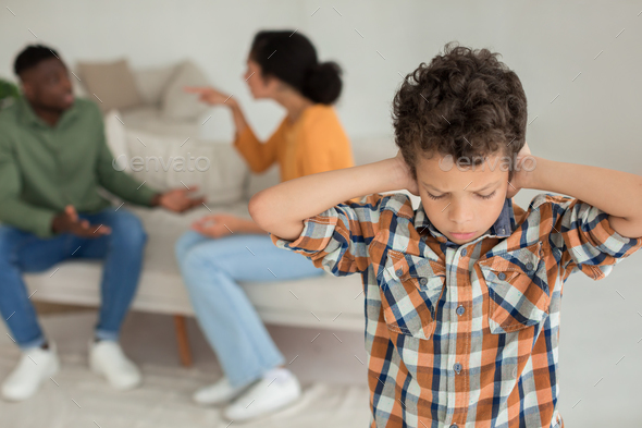 Unhappy Boy Pressing Hands To Ears Listening Parents Conflict Indoor