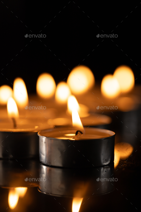 Lit tea candles and candles with copy space on black background Stock Photo  by Wavebreakmedia