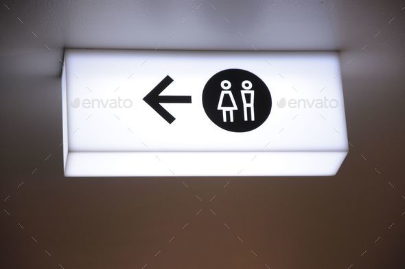 Neon light signboard with male and female symbols and arrow showing to the left