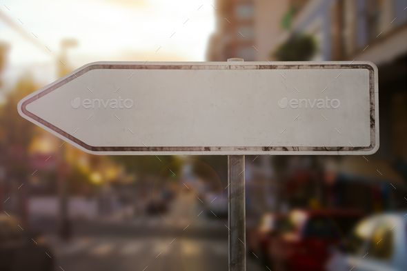 Closeup of a blank direction sign with an arrow to the left in a city at sundown - Stock Photo - Images