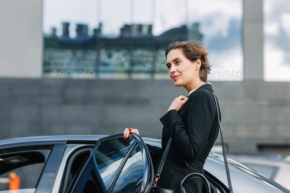 Businesswoman opening a door and entering a taxi