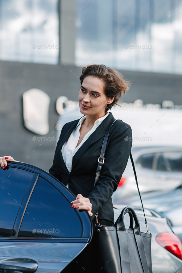Caucasian businesswoman standing at the taxi. Young female entering a car.