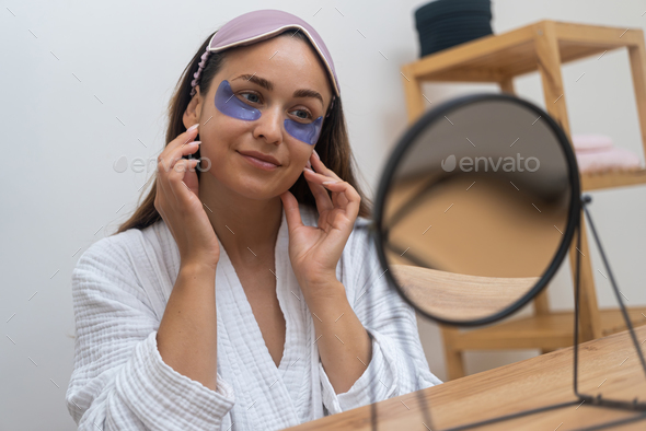 woman, gazing in the mirror, applies under-eye masks for, wrinkles, dark circles eye patches.