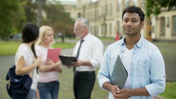 Mixed-race male student smiling into camera, higher education and future alt