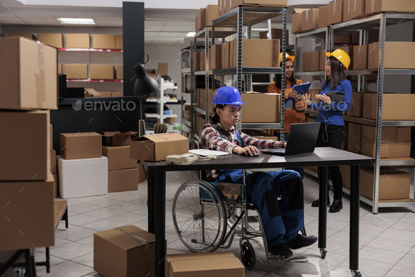 Storehouse employee with disability managing delivery operations on laptop