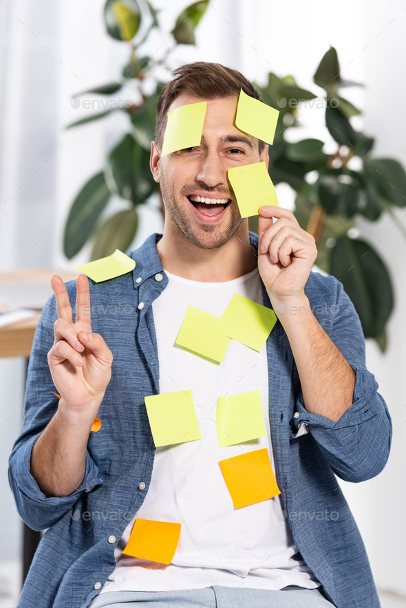 happy man in yellow and orange sticky notes showing peace sign