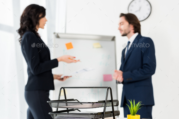 selective focus of document tray near man and woman standing near white board