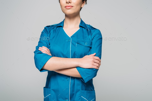 cropped view of young mixed race nurse posing at camera with crossed arms  isolated on grey