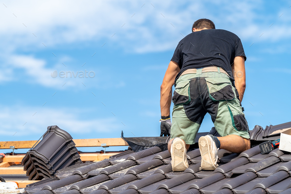 a craftsman works on the roof of a house with a ceramic tile