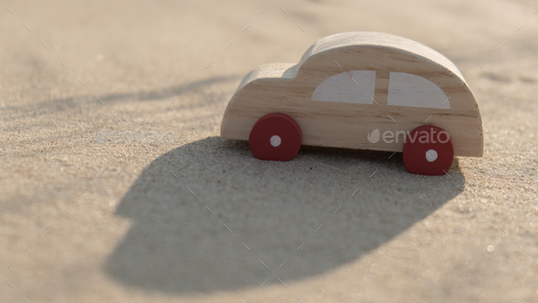 Wooden toy car on sandy beach background. Eco-friendly travel, reduce carbon footprints