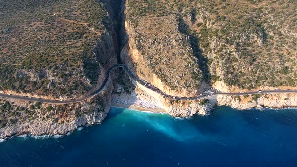 People Swim on Light Blue Sea in the White Sandy Beach Near the Rocky Mountainside alt