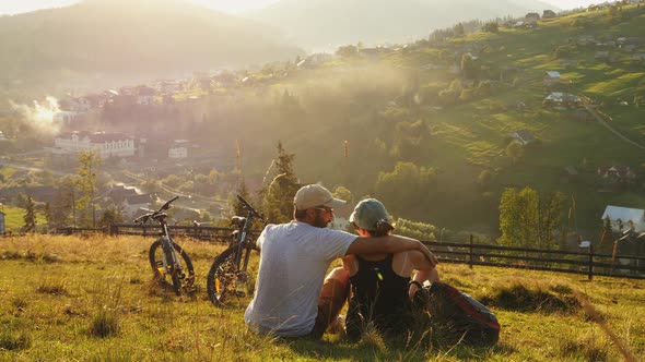 Couple of Tourists Riding a Bicycle Rest on the Hill alt