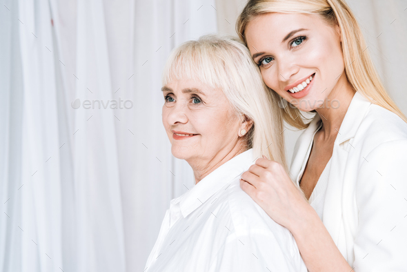elegant blonde granddaughter hugging smiling grandmother