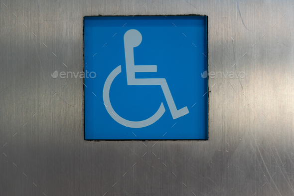 Blue accessibility sign attached to silver wall of modern building on city street