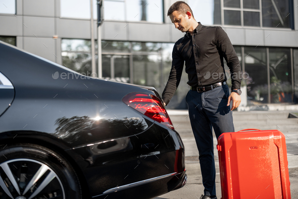 Chauffeur packs a suitcase into luxury car