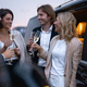 Group of business partners celebrating with alcohol near cars at night - PhotoDune Item for Sale