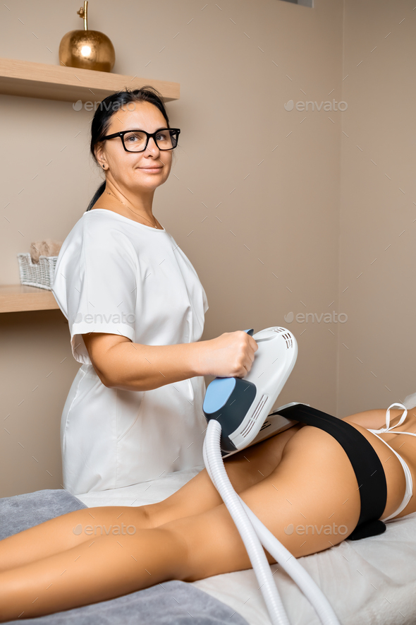 A spa salon professional employs her expertise to perform body sculpting on her clients buttocks.
