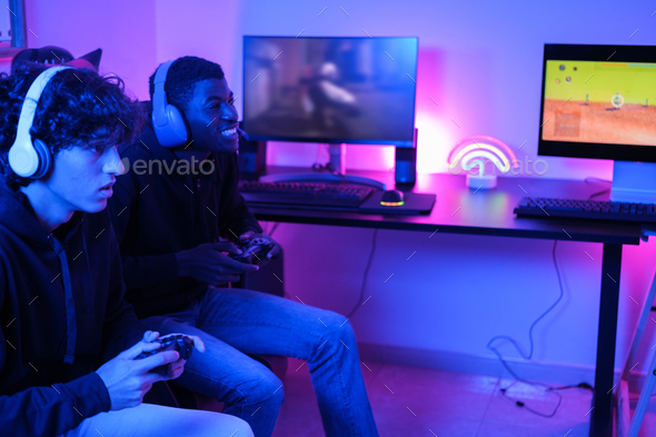 Two young teenagers playing video games online in their gaming room and playing with all countries