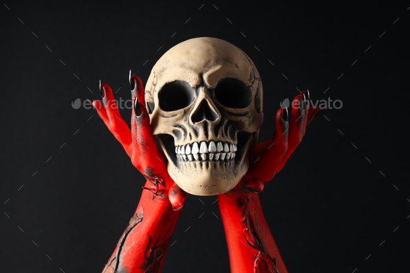 Creepy, red hands of the monster hold the skull
