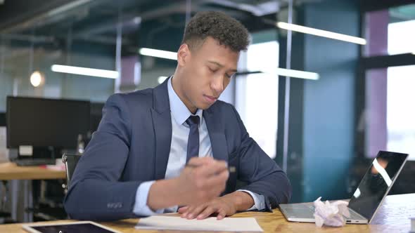 Disappointed Young Businessman Trying To Write on Paper  alt