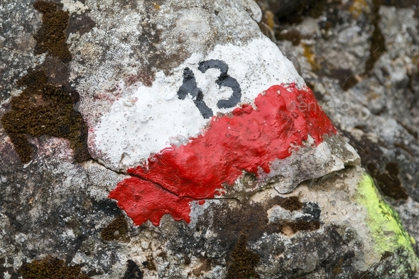 High angle shot of a NO 13 sign on white and red lines painted the rocks