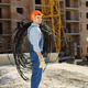 Worker in orange helmet at a construction site holding a wire - PhotoDune Item for Sale