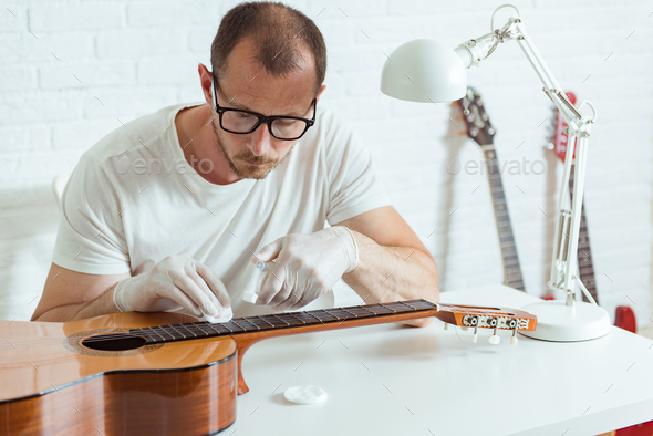 Guitar repairer is cleaning classical guitar, clean cloth to wipe the fretboard