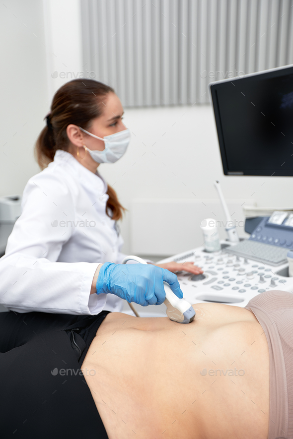 Female doctor gives the patient a female abdominal ultrasound. Ultrasound scanner in the hands of a