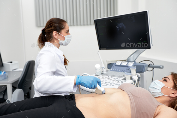 Female doctor gives the patient a female abdominal ultrasound. Ultrasound scanner in the hands of a