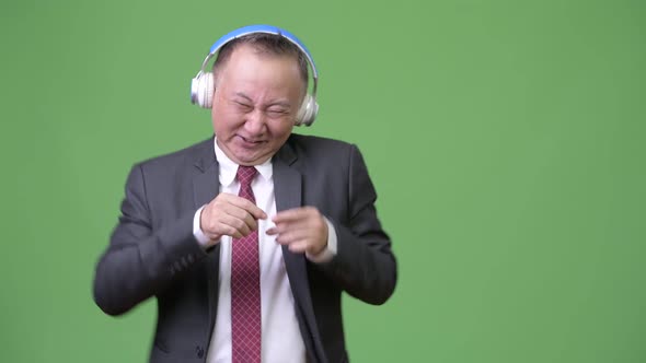 Mature Japanese Businessman Listening To Music alt