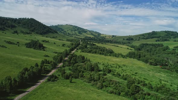 Road in the Green Valley Between Hills alt