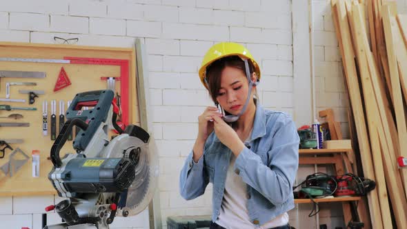 Asian Carpenter woman wearing a helmet before starting working in the wood workshop