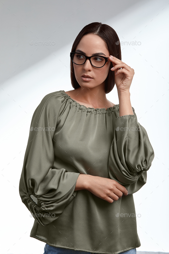 Stylish young brunette in a green dress and glasses, magazine cover, fashion industry, successful