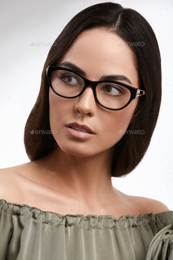 Stylish young brunette in a green dress and glasses, magazine cover, fashion industry, successful