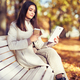 Young  beauty woman sitting with a cup of coffee on a bench in the fall park - PhotoDune Item for Sale