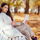 Young  beauty woman sitting with a cup of coffee on a bench in the fall park - PhotoDune Item for Sale