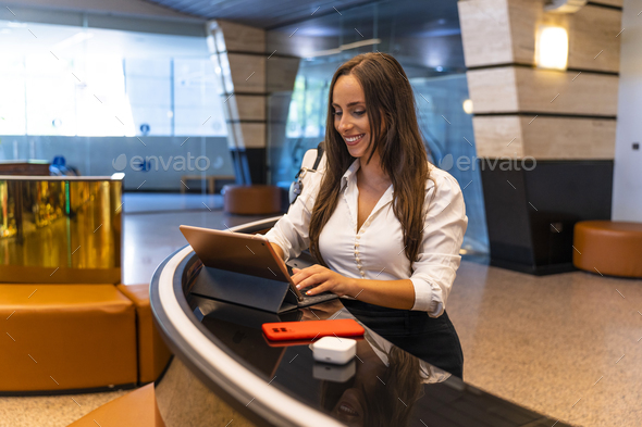 Spanish Businesswoman. Hotel counter. Hotel worker reviewing the day\'s reservations.