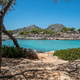 Aponisos beach Agistri island Greece. Rocky beach with pine tree people swim in sea water, sunny day - PhotoDune Item for Sale
