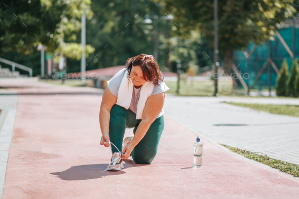 An overweight woman ties his shoelaces through outdoor exercise