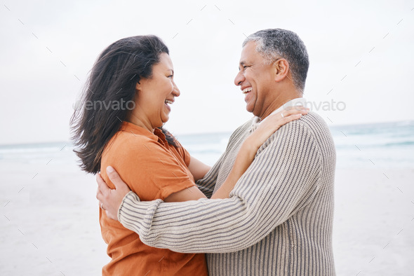 Hug, beach and elderly couple laugh at funny conversation, retirement joke or anniversary humour in