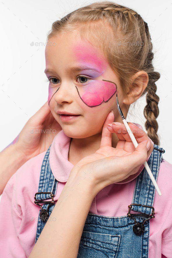 cropped view of artist painting butterfly on face of adorable kid isolated on white