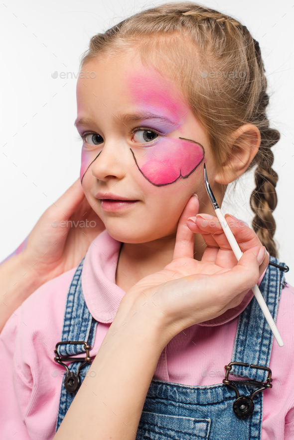 partial view of artist painting butterfly on face of adorable kid isolated on white