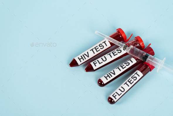 top view of syringe on samples with hiv test and flu test lettering on blue