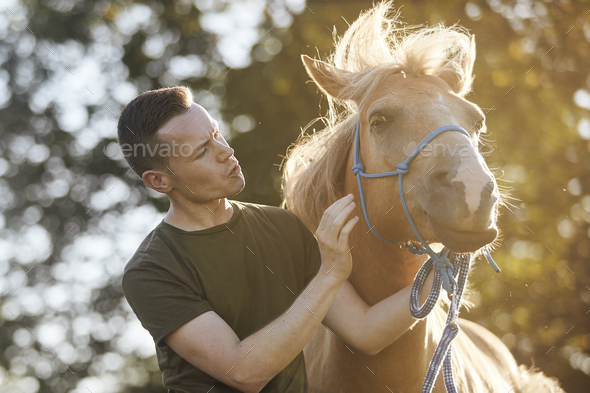 Man calming horse during obedience training